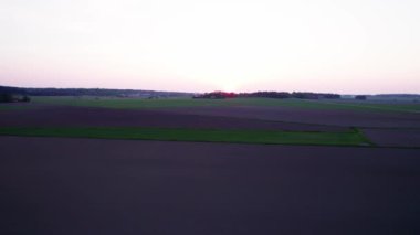 Gün batımında tarlanın üzerinde uçmak. Bu büyüleyici hava görüntüleriyle kırsal alanların dingin güzelliğini deneyimleyin. Yüksek kalite 4k görüntü.