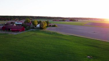 Gün batımında köye uçuyorum. Bu büyüleyici hava görüntüleriyle kırsal alanların dingin güzelliğini deneyimleyin. Yüksek kalite 4k görüntü.