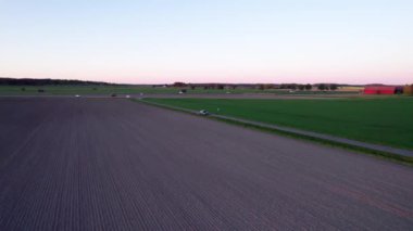 Tarlanın üzerinden yola uçuyor. Yüksek kalite 4K görüntü. İnsansız hava aracı ekinlerin üzerinde yavaşça süzülürken hafif esintiyi hissedebilir ve doğanın fısıltılarını duyabilirsiniz..