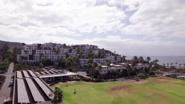 Kurak volkanik tepeler ve Fuerteventura, Kanarya Adaları 'nda dağ yamacına inşa edilmiş beyaz evlerle çevrili manzaralı Playitas Golf Sahası' nı gösteren insansız hava aracı görüntüleri. Pürüzsüz sinematik hareketlerle gün ışığında yakalandılar..