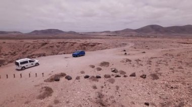 Hava aracı, kırmızı volkanik kıyı şeridini ve El Cotillo, Fuerteventura yakınlarındaki ıssız bir çöl yolunu yakalıyor. Minimalist, kuru arazi denize doğru uzanır ve Kanarya Adaları 'nın saf güzelliğini ortaya çıkarır..