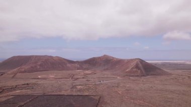 İnsansız hava aracı Fuerteventura 'daki Calderon Hondo yakınlarında engebeli volkanik topraklar boyunca uçuyor. Sert çöl manzarası kıvrımlı yollar ve volkanik aktivite tarafından şekillendirilmiş kızıl tepeler içerir..