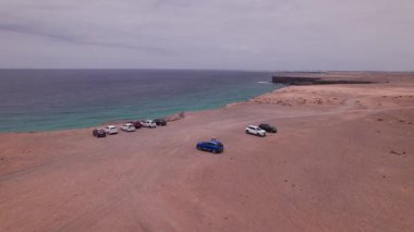 Fuerteventuras 'ın batı kıyısındaki kumsalda uçan insansız hava aracı görüntüleri. Geniş altın plaj, güçlü dalgalar ve volkanik kayalıklar çarpıcı, vahşi bir manzara yaratır..