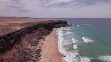 İnsansız hava aracı görüntüleri Fuerteventura 'nın kuzeybatısındaki Playa de la Escalera' daki çöl gibi kıyı şeridini gösteriyor. Dramatik uçurumlar ve kırmızımsı volkanik toprak Atlantik Okyanusu 'yla birleşerek vahşi ve el değmemiş bir manzara yaratıyor..