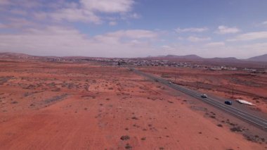 Sinema insansız hava aracı Fuerteventura 'nın kırmızı volkanik arazisini keserek dar bir yolda uçuyor. Çorak, çöl benzeri manzara ufka doğru uzanır parlak bir gökyüzünün altındaki dağlar engebeli ve güzel adayı kaplar.. 