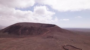 Drone görüntüleri Calderon Hondo 'yu gösteriyor. Kuzey Fuerteventura' nın çorak arazisinden yükselen mükemmel şekilli bir volkanik krater. Geniş açı, hareketsiz volkanı çevreleyen dramatik araziyi, kızıl toprağı ve lav alanlarını yakalar..
