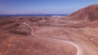 Dikey dron görüntüsü Fuerteventura 'nın derin kırmızı volkanik arazisini yakalıyor. Video, adanın dramatik jeolojisine benzersiz bir perspektif sunarak gerçeküstü, soyut doğal desenler ve çatlak dokular sergiliyor.. 