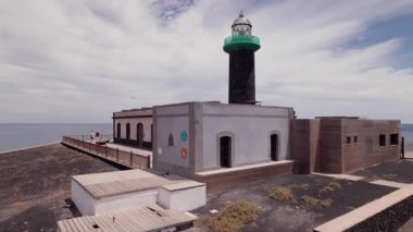 İHA görüntüleri, Fuerteventura 'nın en güney ucundaki tarihi deniz feneri Faro Punta de Jandia üzerinde uçuyor. Çöl arazisiyle çevrili ve okyanusla buluşan ada, ham, el değmemiş bir kıyı manzarası sunuyor.. 