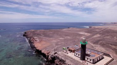 Fuerteventura 'nın güney ucundaki ikonik Faro Punta de Jandia deniz fenerinin hava görüntüleri. Vahşi bir volkanik kıyı şeridi ve çarpan dalgalarla çevrili bu drone atışı Kanarya Adaları 'nın uzak güzelliğini yakalar.. 