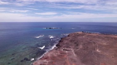 Güney Fuerteventura 'nın çöl manzarasının güçlü Atlantik Okyanusu ile buluştuğu Faro Punta de Jandia' nın sinematik drone görüntüleri. Deniz feneri ve engebeli arazi dramatik ve izole bir manzara yaratır.. 
