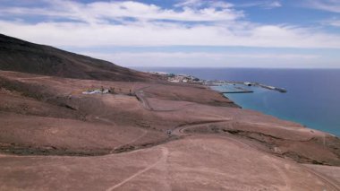 Güney Fuerteventura 'da Morro Jable ve Jandia arasındaki kurak çöl arazisine uzanan asfaltsız yolun insansız hava aracı görüntüleri. Sinema filmi Kanarya Adaları 'nın engebeli ve izole güzelliğini gözler önüne seriyor.. 