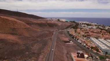 Fuerteventura 'nın güney ucundaki Morro Jable' ın uzak bir görüntüsünü yakalıyorum. Kıyı kasabası volkanik tepeler, kuru çöl manzarası ve uçsuz bucaksız Atlantik Okyanusu ile çevrilidir. Kanarya Adaları 'na manzaralı ve izole bir bakış açısı. 