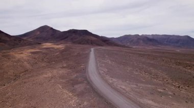 İnsansız hava aracı, Jandia çölünde uzanan uzun toprak bir yol yakalıyor. Volkanik topraklar boyunca uzanan yol, Fuerteventura 'nın güneyine doğru uzanan hiçbir uygarlık belirtisi göstermiyor.. 