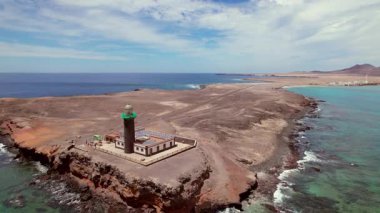 Faro de Jandia deniz fenerini çeken hava görüntüleri, turkuaz Atlantik Okyanusu 'nun üzerindeki dramatik kırmızı volkanik kayalıklara tünedi. Fuerteventura 'nın uzak güneybatı ucunda yer alan bu ikonik sahne, engebeli doğayı kültürel cazibeyle harmanlıyor..
