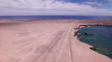 Fuerteventura 'nın güneyindeki Playa de Soledad boyunca alçak uçuş. Çöl uçurumları, kumlu pistler ve mavi gökyüzü altında Atlantik dalgaları..