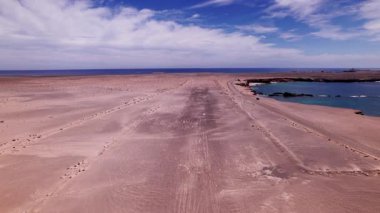 Fuerteventura 'daki Playa de Soledad yakınlarında terk edilmiş bir havaalanı boyunca İHA uçuşu. Volkanik arazi, kayalıklar ve mavi Atlantik dalgaları bu eşsiz kumsalı çevreledi..