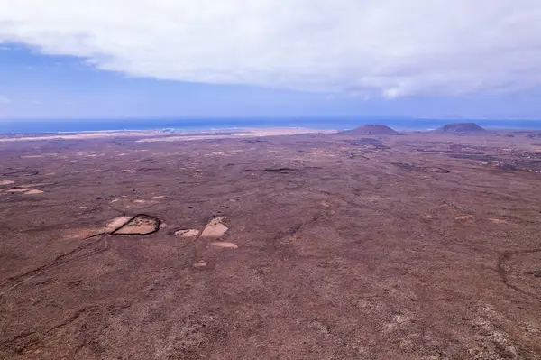 Güney Fuerteventura 'daki kırmızı volkanik arazi ve çöl dağlarının insansız hava aracı görüntüsü. Sert doku ve doğal izolasyon bu dramatik manzarayı tanımlar..