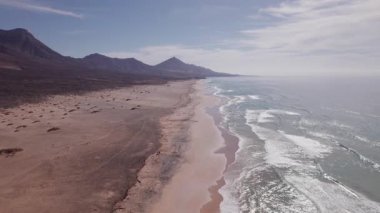 Gün batımının ılık renklerini gösteren hava videosu Playa de Coffee 'nin plajını ve Fuerteventura' nın çevresini aydınlatıyor.. 