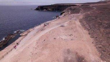 Fuerteventura 'daki Ajuy Mağaraları' nın yakınındaki manzaralı kıyı yolunu gösteren muhteşem hava görüntüleri. Görüntü, engebeli uçurumları, derin mavi okyanusları ve kurak manzaraları sergiliyor. Seyahat, doğa ve macera fotoğrafçılığı için mükemmel.. 