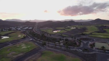 Gün batımında Fuerteventuras 'ın yuvarlanan tepeleri ve yemyeşil alanları gösteren muhteşem hava görüntüleri. Görüntü, doğa ve insan yapımı yapıların uyumlu bir karışımını sergiliyor, seyahat ve yaşam tarzı fotoğrafçılığı için mükemmel..