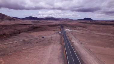 Detaylı hava görüntüleri Fuerteventura 'nın engebeli, çorak arazisini kesen düz bir yol yakalıyor. Görüntü, kırmızı toprağın, dağınık bitki örtüsünün ve uzak dağların katıksız güzelliğini vurguluyor. Bu da onu seyahat fotoğrafçılığı için ideal kılıyor..