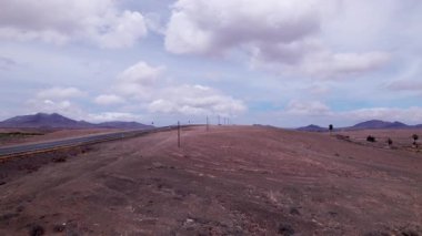 Dinamik hava çekimi Fuerteventura 'daki uzak ufka doğru uzanan düz bir yol gösteriyor. Görüntü Kanarya Adaları 'nın saf güzelliğini yansıtıyor. Seyahat, doğa ve macera içeriği için ideal..