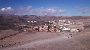 Fuerteventura 'daki La Pared' in fevkalade köyünü gösteren muhteşem hava görüntüleri. Görüntü, binaların canlı renklerini, kurak manzarayı ve hareketli tepeleri sergiliyor. Seyahat, gayrimenkul ve yaşam tarzı fotoğrafçılığı için mükemmel.. 