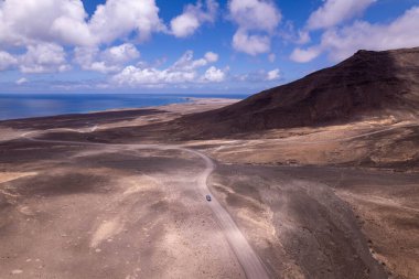 Dinamik hava çekimi Jandia, Fuerteventura 'da ufka doğru uzanan düz bir yol gösteriyor. Görüntü, yapılandırılmış yol ile engebeli arazi arasındaki zıtlığı, seyahat, emlak ve yaşam tarzı fotoğrafçılığı için ideal olanı yakalıyor.. 