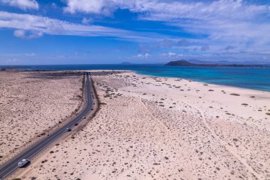 Detaylı hava görüntüleri Corralejo, Fuerteventura 'da okyanus kenarında bir viraj yolu yakalıyor. Görüntü, turkuaz suların yapılandırılmış yolu ile doğal güzelliği arasındaki zıtlığı vurguluyor. Bu da onu seyahat ve yaşam tarzı içeriği için ideal yapıyor..