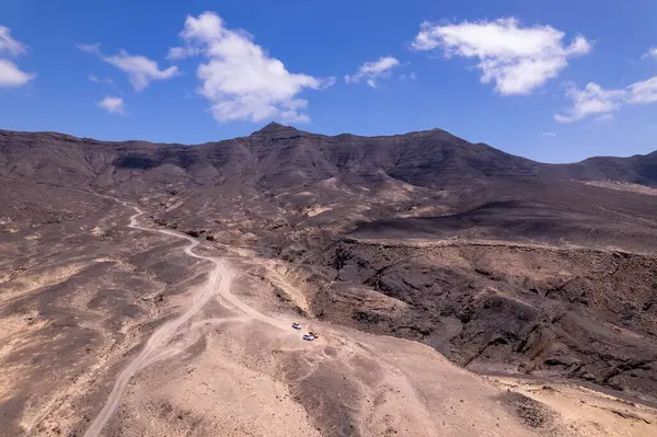 Muhteşem hava görüntüleri, Fuerteventura 'daki Playa de Coffee' de Roque del Moro kıyısında bir kavis çiziyor. Görüntü kırmızı toprağın, dağınık bitki örtüsünün ve uzak tepelerin katıksız güzelliğini sergiliyor. Seyahat fotoğrafçılığı için mükemmel. 