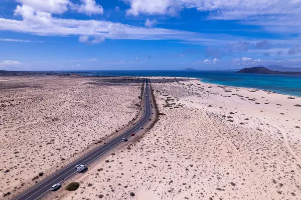 Fuerteventura, Corralejo 'da ufka uzanan düz bir yol yakalayan muhteşem hava görüntüleri. Görüntü, yapılandırılmış yol ve engebeli arazi arasındaki kontrastı gösteriyor. Seyahat ve yaşam tarzı fotoğrafçılığı için mükemmel.. 