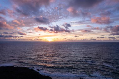 Dinamik hava çekimi Fuerteventura 'daki La Pared' in kurak arazisinin yakınında çarpıcı günbatımını gösteriyor. Görüntü, seyahat ve yaşam tarzı fotoğrafçılığı için ideal olan altın kumlar, turkuaz sular ve engebeli tepeler arasındaki zıtlığı yakalıyor.. 