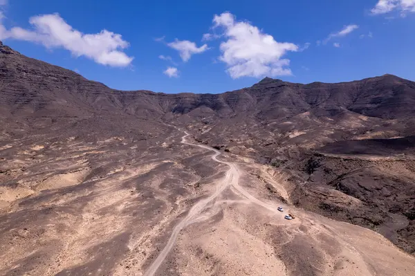 Detaylı hava görüntüleri Fuerteventura 'daki Playa de Cofete' de Roque del Moro 'nun sahil kayalıkları yakınlarında bir viraj yolu yakalıyor. Görüntü, yapılandırılmış yol ile engebeli arazi arasındaki zıtlığı vurguluyor ve bu da onu seyahat içeriği için ideal hale getiriyor. 