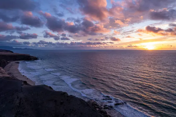Volkanik kayalıklar ve kıyı şeridi Fuerteventura, Kanarya Adaları 'nda altın gün batımı ışığında yıkandı.. 
