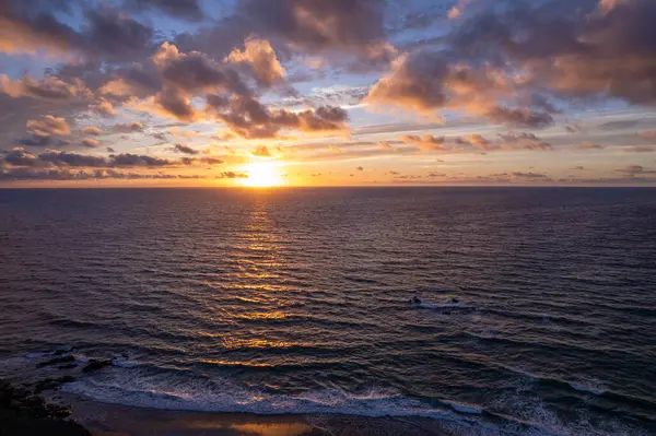 İspanya, Fuerteventura 'da gün batımında parlak altın ve turuncu gökyüzü yansıyor.. 