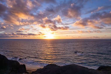 Altın saat günbatımı Fuerteventura 'da La Pared yakınlarındaki turkuaz sularda ılık renkler bırakıyor. Bu sakin sahne ışık ve gölgenin etkileşimini yakalar. Seyahat, doğa ve ilham verici fotoğrafçılık için mükemmeldir.. 