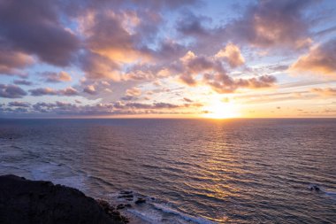 Fuerteventura 'daki La Pared' in uzak dağlarının yakınlarındaki çarpıcı günbatımını gösteren muhteşem hava görüntüleri. Görüntü kırmızı toprağın katıksız güzelliğini sergiliyor, dağınık bitki örtüsü, ve uzak tepeler, seyahat fotoğrafçılığı için mükemmel.. 