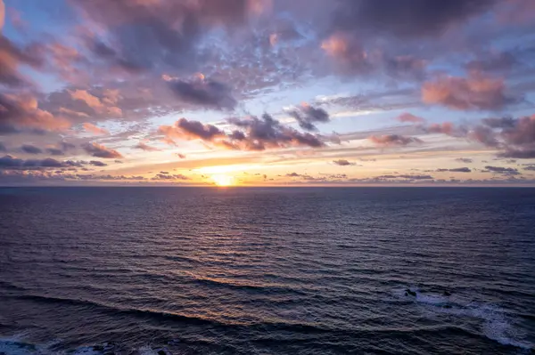 Detaylı hava görüntüleri Fuerteventura 'da La Pared yakınlarında sakin günbatımını dramatik bir gökyüzü ile yakalıyor. Görüntü, kırmızı toprağın, dağınık bitki örtüsünün ve uzak tepelerin katıksız güzelliğini vurgular. Bu da onu seyahat için ideal kılar, doğa içeriği..