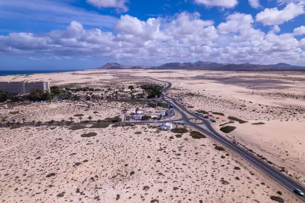 Fuerteventura 'daki Corralejo' nun çarpıcı kum tepelerinin yakınındaki modern bir otelin görüntüsü. Görüntü lüks konaklama ve doğal güzelliğin karışımını sergiliyor, seyahat ve yaşam tarzı fotoğrafçılığı için mükemmel.. 