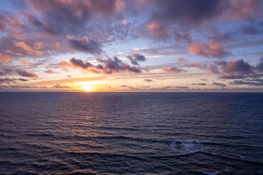 Günbatımı ışığı İspanya 'nın engebeli La Pared kıyısındaki kayalıklara ve denize yansıyor.. 