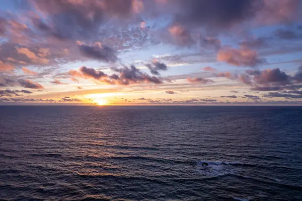 Günbatımı ışığı İspanya 'nın engebeli La Pared kıyısındaki kayalıklara ve denize yansıyor.. 