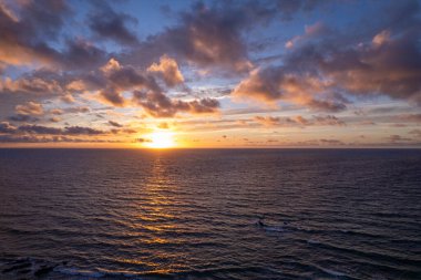 Dinamik hava çekimi Fuerteventura 'daki La Pared' in turkuaz sularının yakınında çarpıcı günbatımını gösteriyor. Görüntü, yapılandırılmış yol ile engebeli arazi arasındaki zıtlığı, seyahat, emlak ve yaşam tarzı fotoğrafçılığı için ideal olanı yakalıyor.. 