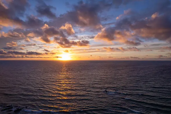Dinamik hava çekimi Fuerteventura 'daki La Pared' in turkuaz sularının yakınında çarpıcı günbatımını gösteriyor. Görüntü, yapılandırılmış yol ile engebeli arazi arasındaki zıtlığı, seyahat, emlak ve yaşam tarzı fotoğrafçılığı için ideal olanı yakalıyor.. 