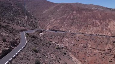 Dinamik hava görüntüleri Fuerteventura 'da çöl arazisini kesen bir yol olduğunu gösteriyor. Görüntü, yapılandırılmış yol ile engebeli arazi arasındaki zıtlığı, seyahat, emlak ve yaşam tarzı fotoğrafçılığı için ideal olanı yakalıyor.. 