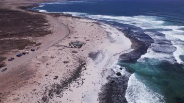 Detaylı hava görüntüleri Fuerteventura 'daki Popcorn Playa del Bajo de la Burra sahilinin yakınındaki kurak araziyi gösteriyor. Görüntü, kırmızı toprağın, dağınık bitki örtüsünün ve uzak tepelerin katıksız güzelliğini vurgular..