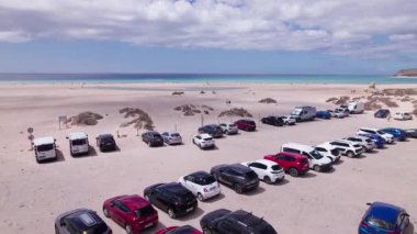Dinamik hava görüntüleri, park alanından Fuerteventura 'daki Costa Calma' daki güzel plaja kadar pürüzsüz bir uçuş olduğunu gösteriyor. Görüntü, yapılandırılmış park alanından engebeli araziye ve sakin okyanus manzarasına geçişi yakalıyor..