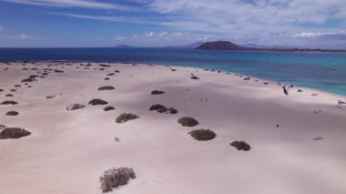 Detaylı hava görüntüleri Fuerteventura 'daki sörf sahasının yakınındaki kurak araziyi gösteriyor. Görüntü, kırmızı toprağın, dağınık bitki örtüsünün ve uzak tepelerin katıksız güzelliğini vurguluyor. Bu da onu seyahat, doğa ve macera içeriği için ideal kılıyor.
