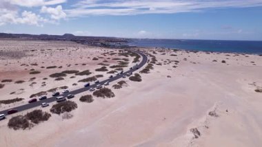 Fuerteventura sahilinin yakınındaki büyüleyici köyü gösteren detaylı hava görüntüleri. Görüntü, kırmızı toprağın, dağınık bitki örtüsünün ve uzak tepelerin katıksız güzelliğini vurguluyor. Bu da onu seyahat, doğa ve macera içeriği için ideal kılıyor.. 