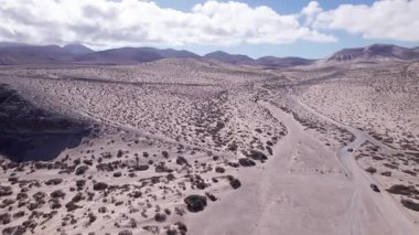 Fuerteventura 'daki kurak çöl manzarasında nefes kesen gün batımını çeken muhteşem hava görüntüleri. Görüntü gökyüzünün canlı renklerini sergiliyor, dağınık bitki örtüsü, ve uzak tepeler, seyahat için mükemmel, doğa fotoğrafçılığı.