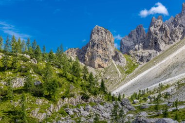 Dolomiti Alpleri güzel dağ manzarası. Dolomitlerde Rocky kulesi zirveleri. Yeşil dağ vadisindeki yürüyüş yolunda yaz manzarası ve bulutlu mavi gökyüzü.